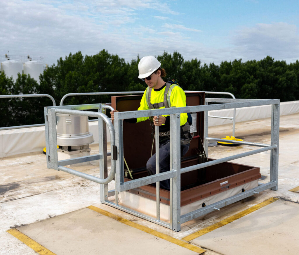 man walking through rooftop hatch using railing on hatchguarding