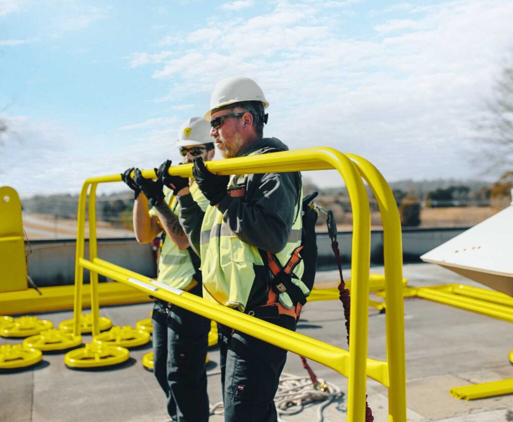 two installers on rooftop installing SRC360 safety railing